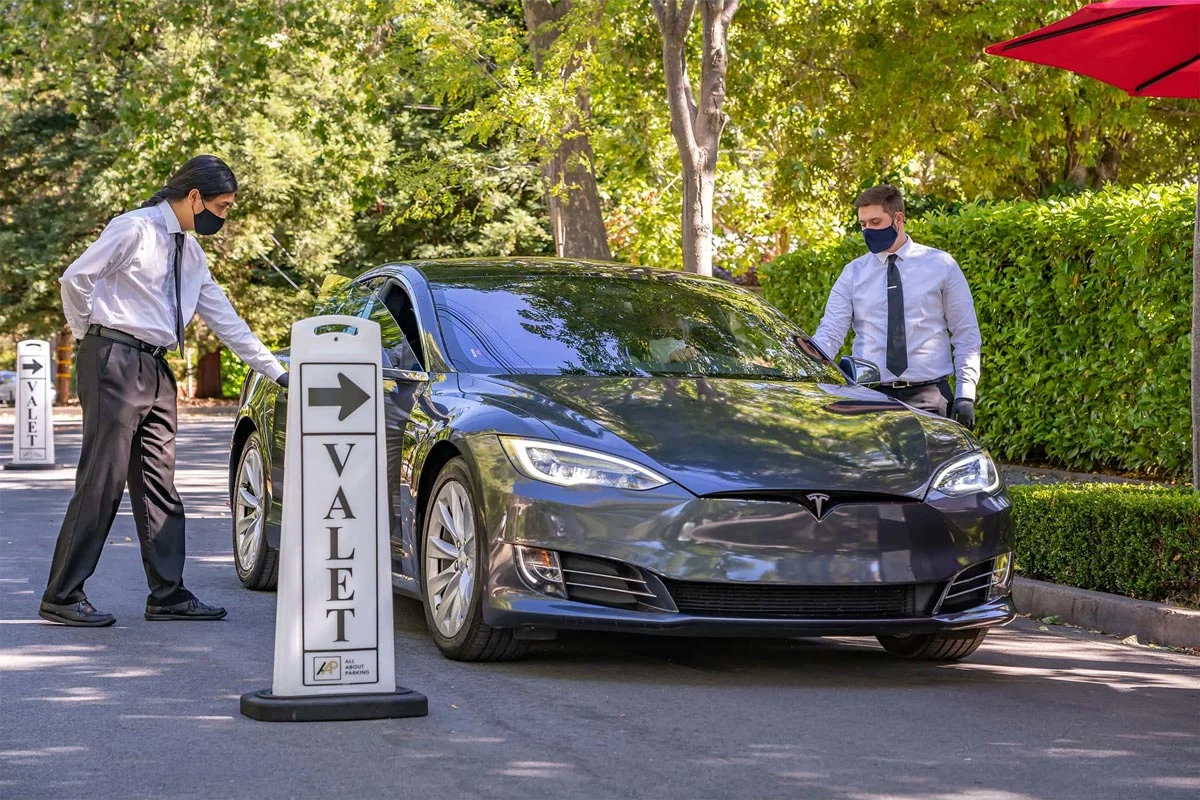 Two valet attendants directing a vehicle at an event entrance